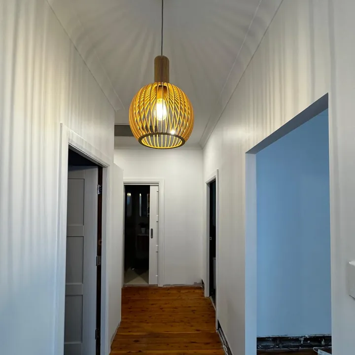 Renovated hallway with smooth white walls, timber floor and a pendant light
