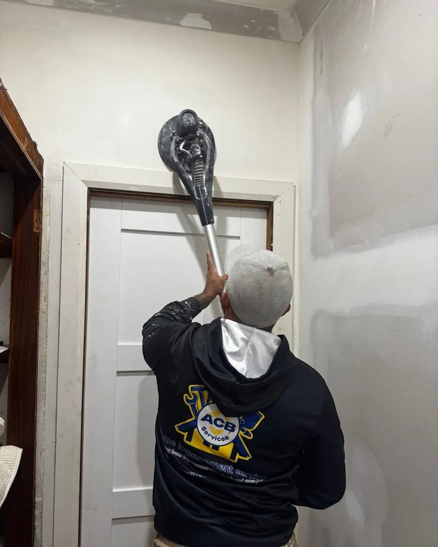 ACB plasterer sanding a new wall with a pole sander